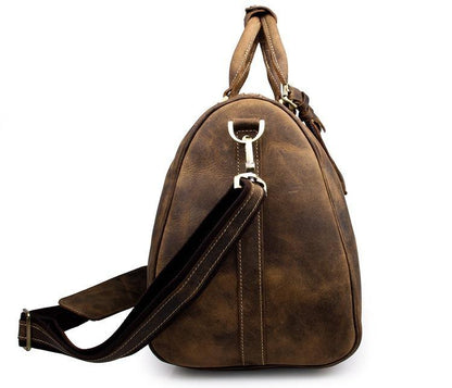 Small leather duffle bag in brown with top handle, shoulder strap, and side hardware