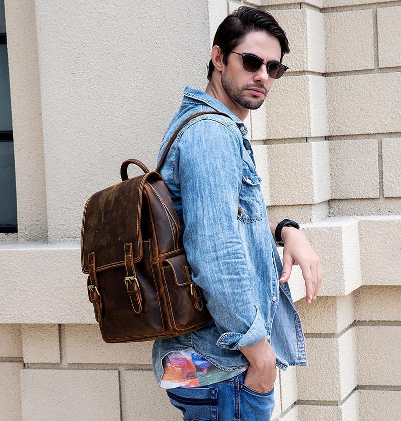 Brown leather backpack worn on shoulder with front buckle details