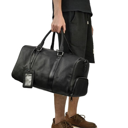 Black leather weekender duffle bag held by a person; top handles and side zipper.