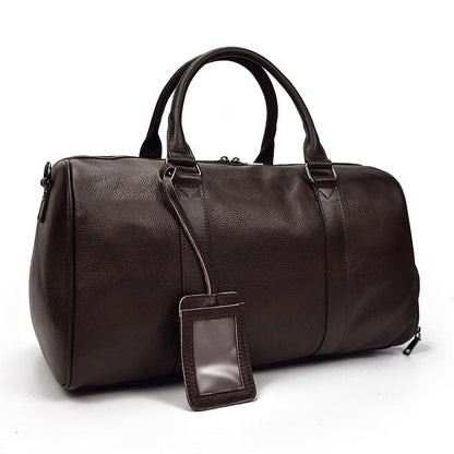 Brown vintage leather weekender duffle bag with top handles and hanging luggage tag