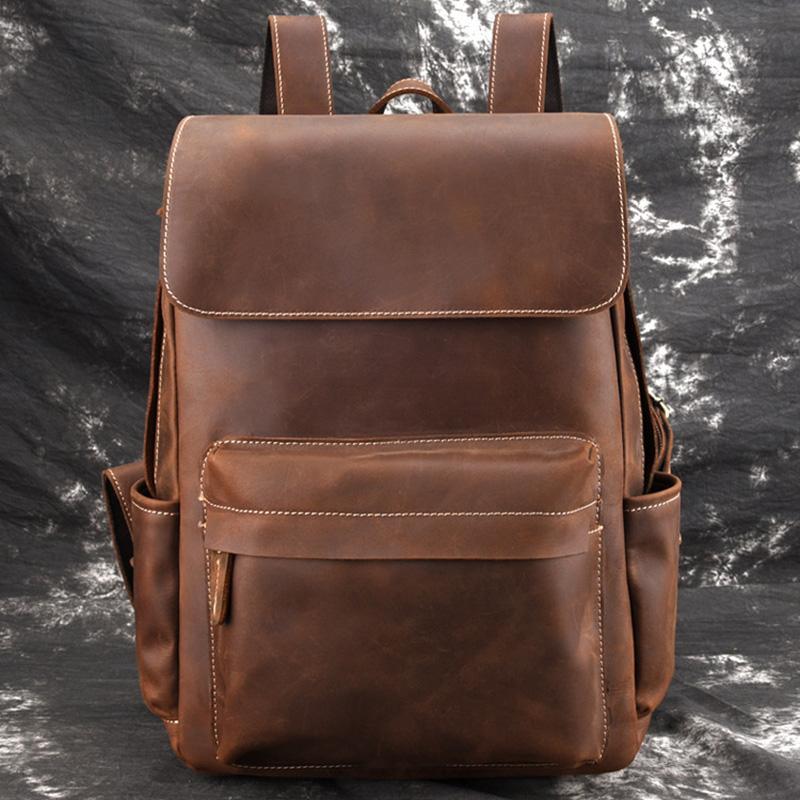 Vintage leather laptop backpack in brown, close front view with flap and stitched pocket.
