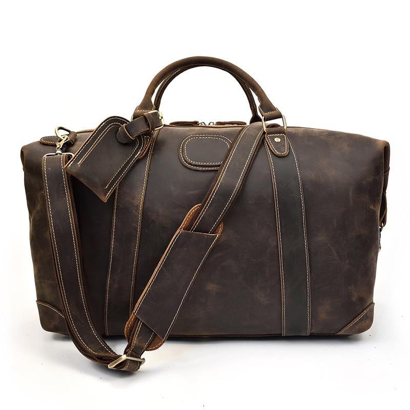 Vintage leather duffle bag in dark brown with crossbody strap and front buckle tags.