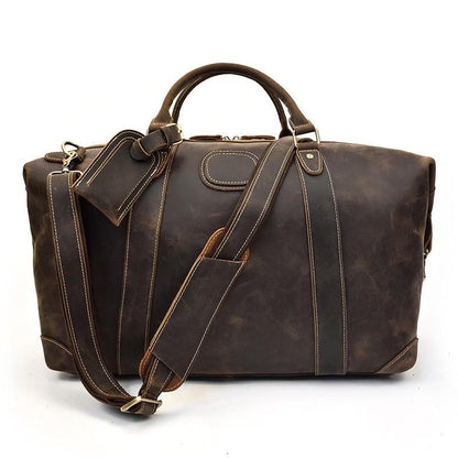Vintage leather duffle bag in dark brown with crossbody strap and front buckle tags.