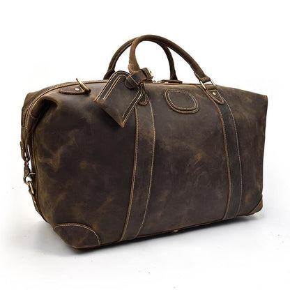 Vintage leather duffle bag with top handle and shoulder strap on left side view.