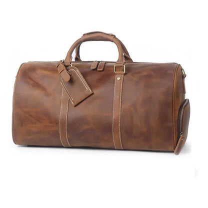 Large brown leather duffle travel bag with front strap detail and side zipper pocket.