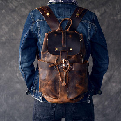 Leather rucksack worn over denim jacket, with front flap pocket and cord draw closure