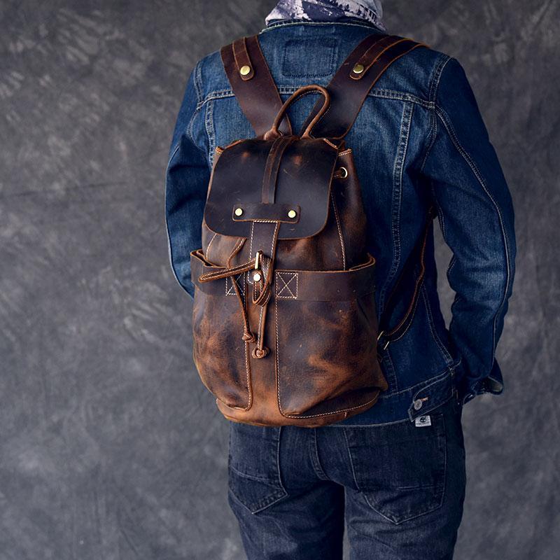 Brown leather rucksack on person, featuring front flap pocket and drawstring cord