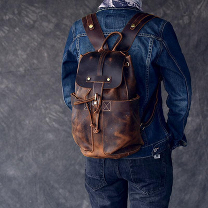 Brown leather rucksack on person, featuring front flap pocket and drawstring cord
