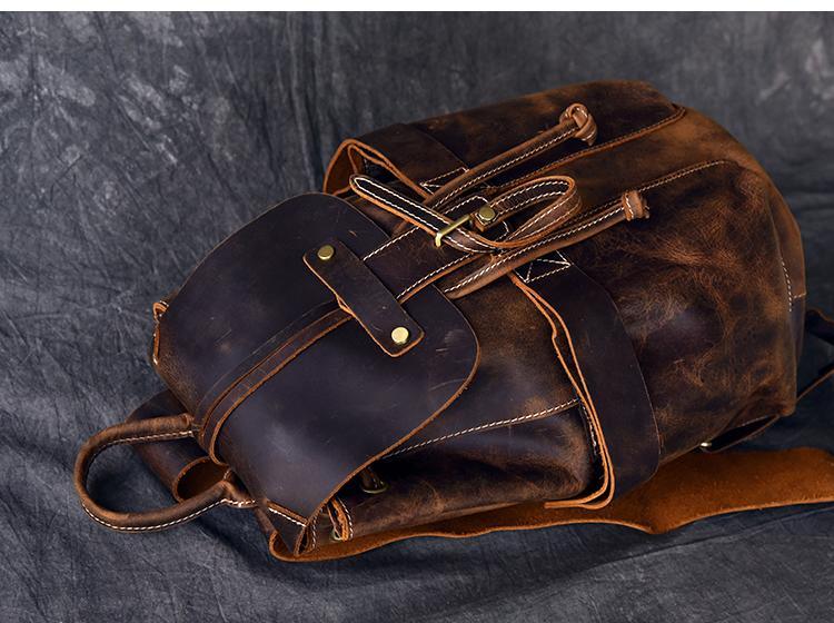 Rolled leather rucksack with side straps, buckle pocket, and stitched details
