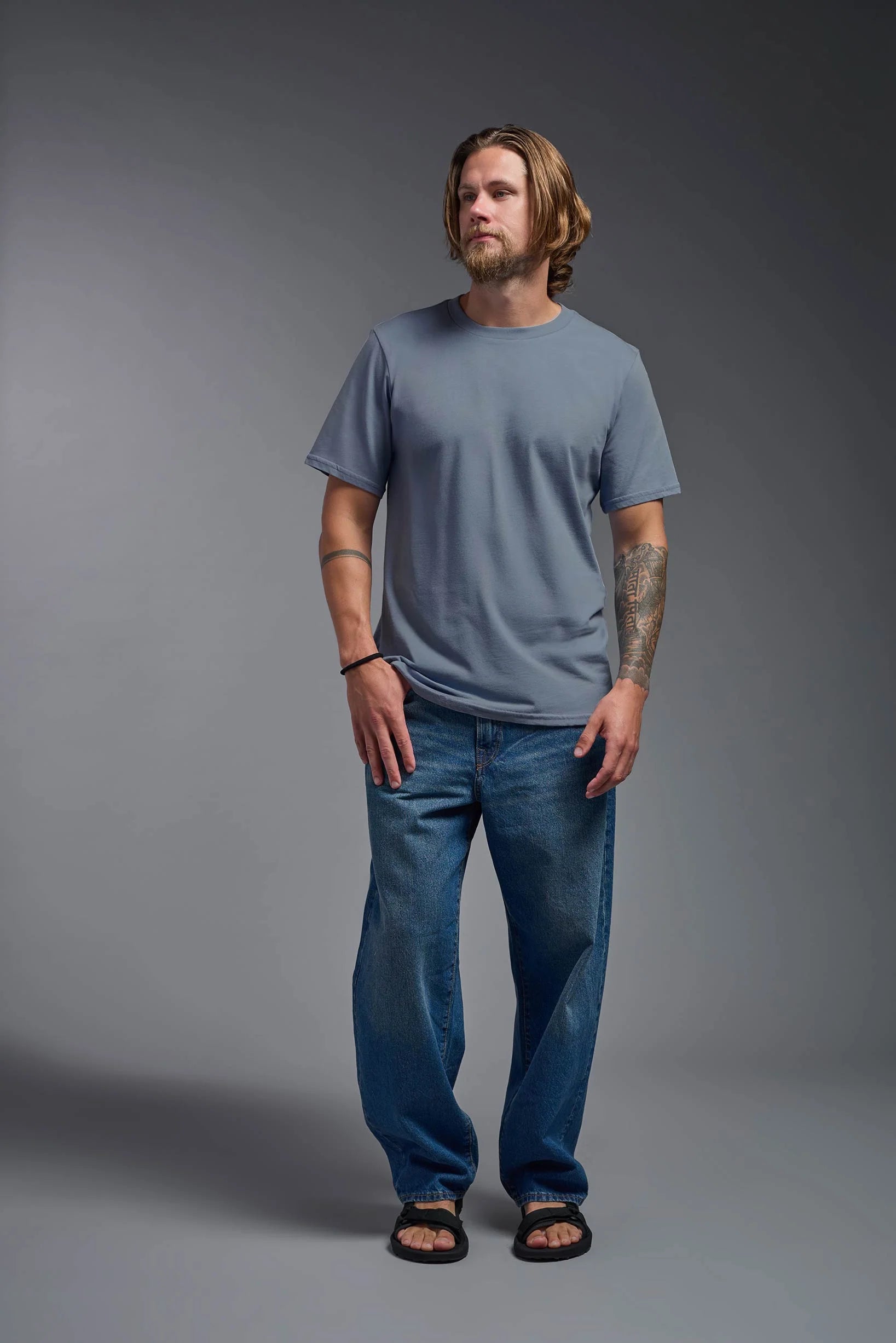 Man wearing a blue t-shirt and jeans against a gray background