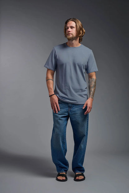 Man wearing a blue t-shirt and jeans against a gray background