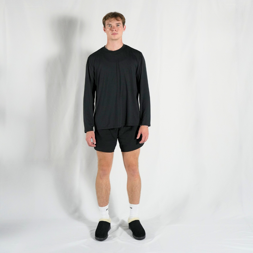 Person wearing a black long-sleeve shirt and shorts on a white background
