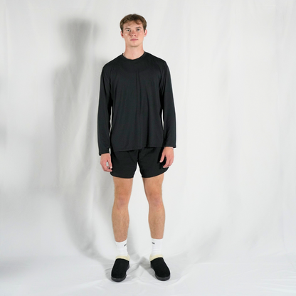 Person wearing a black long-sleeve shirt and shorts on a white background