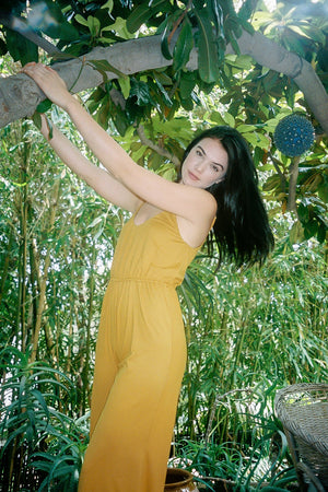 Women's Honey Yellow Jumpsuit with model outside in the woods.